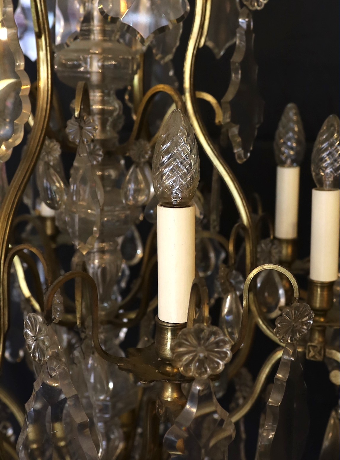 An early 20th century French bronze and cut glass twelve light chandelier, hung with tear, lozenge and flowerhead shaped drops, drop 114cm. width 72cm